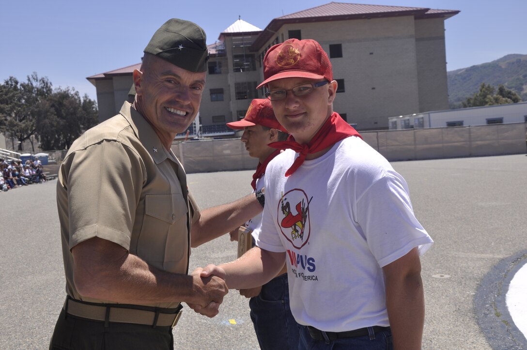 Brig. Gen. Vincent A. Coglianese, commanding general of Marine Corps Installations West - Marine Corps Base Camp Pendleton, shakes hands with Benjamin Hulbert, the 50,000th Devil Pup graduate, during the Devil Pups graduation ceremony on Camp Pendleton's 52 Area Parade Deck, July 28.