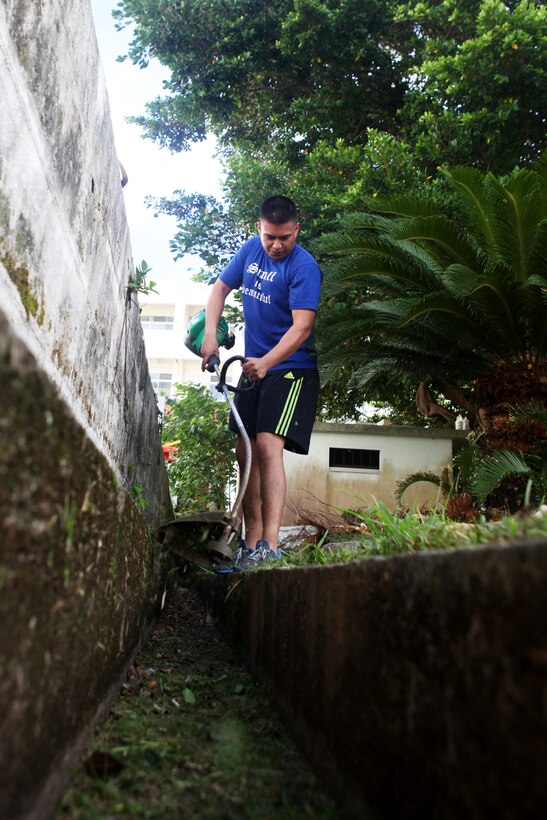 NAHA, Okinawa, Japan -- Corporal Adam Imbriaco, a legal clerk with the command element of the 31st Marine Expeditionary Unit, cuts grass at the Tomari International Cemetery here, July 29. Through the efforts of one young Boy Scout, Gabriel Vasquez, military members from nearly every branch of service came together to revitalize a local cemetery where numerous veterans are buried.