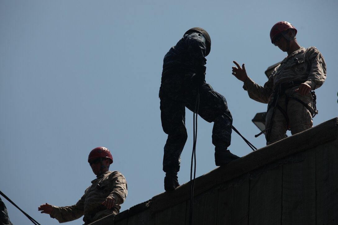 A midshipman prepares to repel down a wall, while listening to the instruction a Marine is giving him aboard Marine Corps Base Camp Lejeune July 24. Many of the midshipmen had never repelled before, so they were eager to learn how.