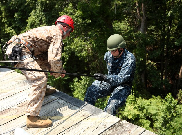 A midshipman begins to repel down a wall, carefully listening to a Marine’s during training aboard Marine Corps Base Camp Lejeune July 24. The repelling went smoothly thanks to the great instruction given by Marines, and the midshipmens’ ability to listen to direction.