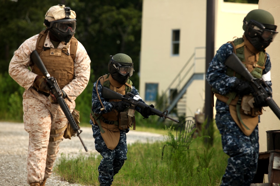 Two midshipmen and a Marine rush around a corner while practicing Military Operations on Urban Terrain aboard Marine Corps Base Camp Lejeune July 25. The midshipmen were educated on how to fight in an urban environment and how to properly clear a room, and they were able to put what they learned to the test.