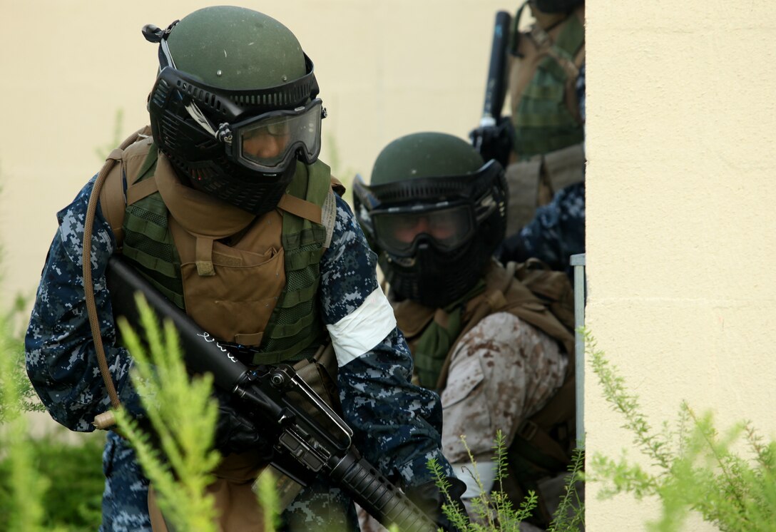 A midshipman looks around a corner before the team advances to make sure the area is free of hostiles while practicing Military Operations on Urban Terrain aboard Marine Corps Base Camp Lejeune July 25. Midshipmen were shown how to advance building by utilizing fire teams, which gave them security as they moved around the simulated town.