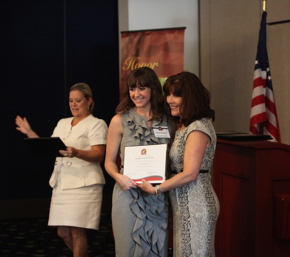 A military child (center) receives a certificate after winning a scholarship from the Marine Corps Scholarship Foundation aboard Marine Corps Base Camp Lejeune July 26. The child was one of 1,909 students whom received a scholarship from the MCSF this year.