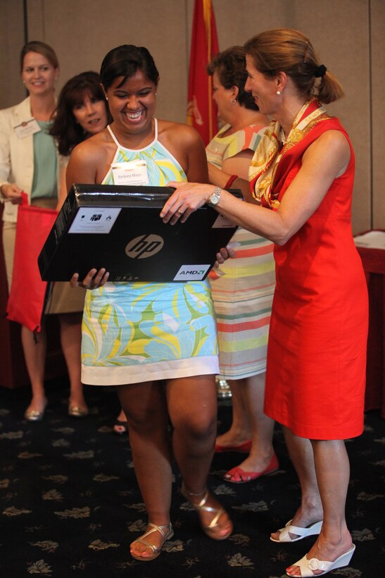 A military child (center) smiles after Marine Corps Scholarship Foundation President Margaret Davis hands her a laptop won in a random drawing aboard Marine Corps Base Camp Lejeune July 26. The child was one of 26 who received a laptop from Hewlett Packard during an MCSF ceremony.