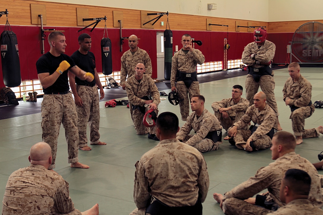 Sgt. Michael T. Ambrose, left, and Staff Sgt. Kennie B. Wade, both wearing black shirts, teach students how to throw an effective punch during a martial arts instructor course at Camp Hansen June 3. Ambrose and Wade are instructor-trainers for the course. Both are with 7th Comm. Bn. 
