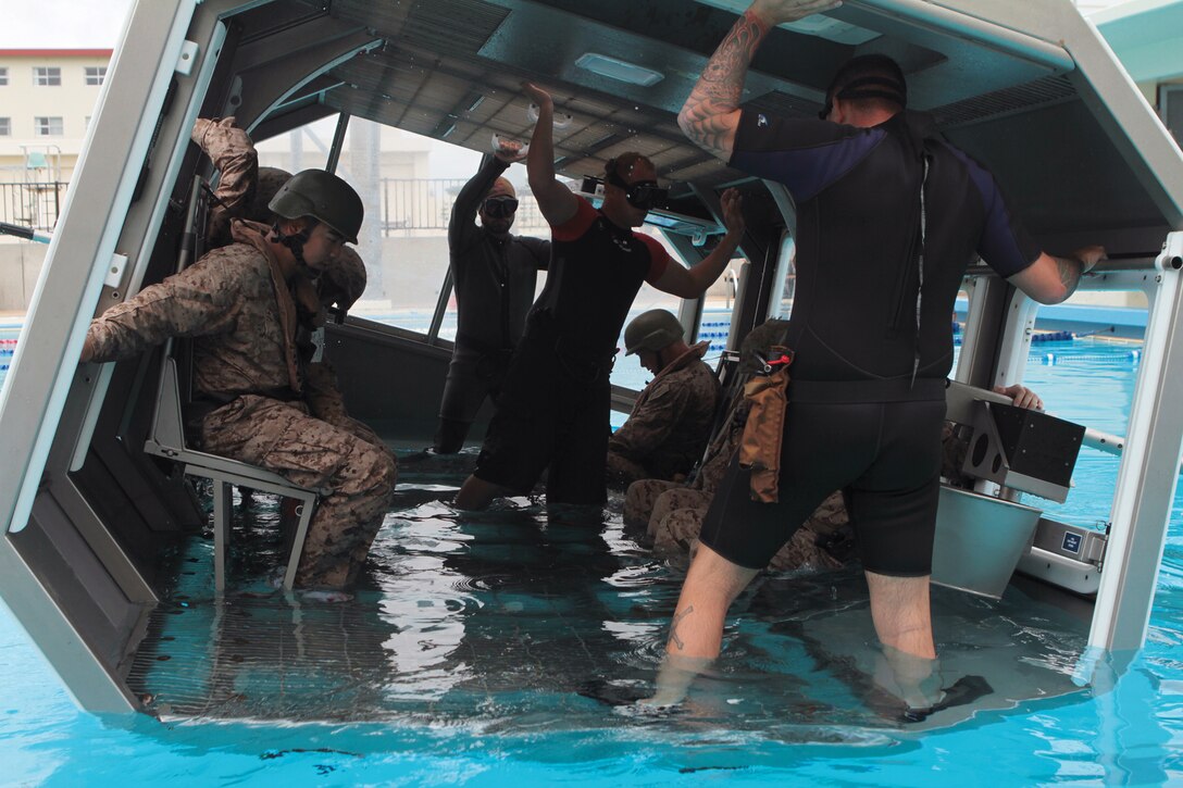 Marines, sailors and instructors brace for submersion during modular amphibious egress training at Camp Hansen June 8. By conducting MAET, the service members ensure they have the skills to escape a sinking helicopter to stay alive. The Marines and sailors are with 3rd Medical Battalion, Combat Logistics Regiment 35, 3rd Marine Logistics Group, III Marine Expeditionary Force. 
