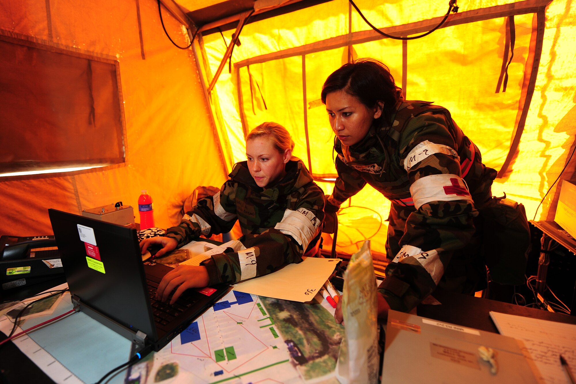 U.S. Air Force Airman 1st Class Christina Claycamp, 55th Medical Operations Squadron, and U.S. Air Force Staff Sgt. Avegail Yabut, 55th Medical Support Squadron, check the status of patients in and around the medical tents of “Base X” as part of an Operational Readiness Exercise at Offutt Air Force Base, Neb., July 27. (U.S. Air Force Photo by Josh Plueger/Released)