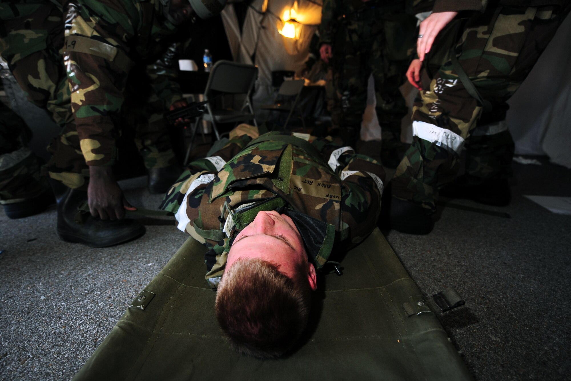 An Airman is laid onto a stretcher inside of the mortuary affairs tent during and Operational Readiness Exercise held at Offutt Air Force Base, Neb., July 27.  The patient, used for training purposes, was taken to the medical tent to have his neck and chest examined following a simulated explosion. (U.S. Air Force Photo by Josh Plueger/Released)