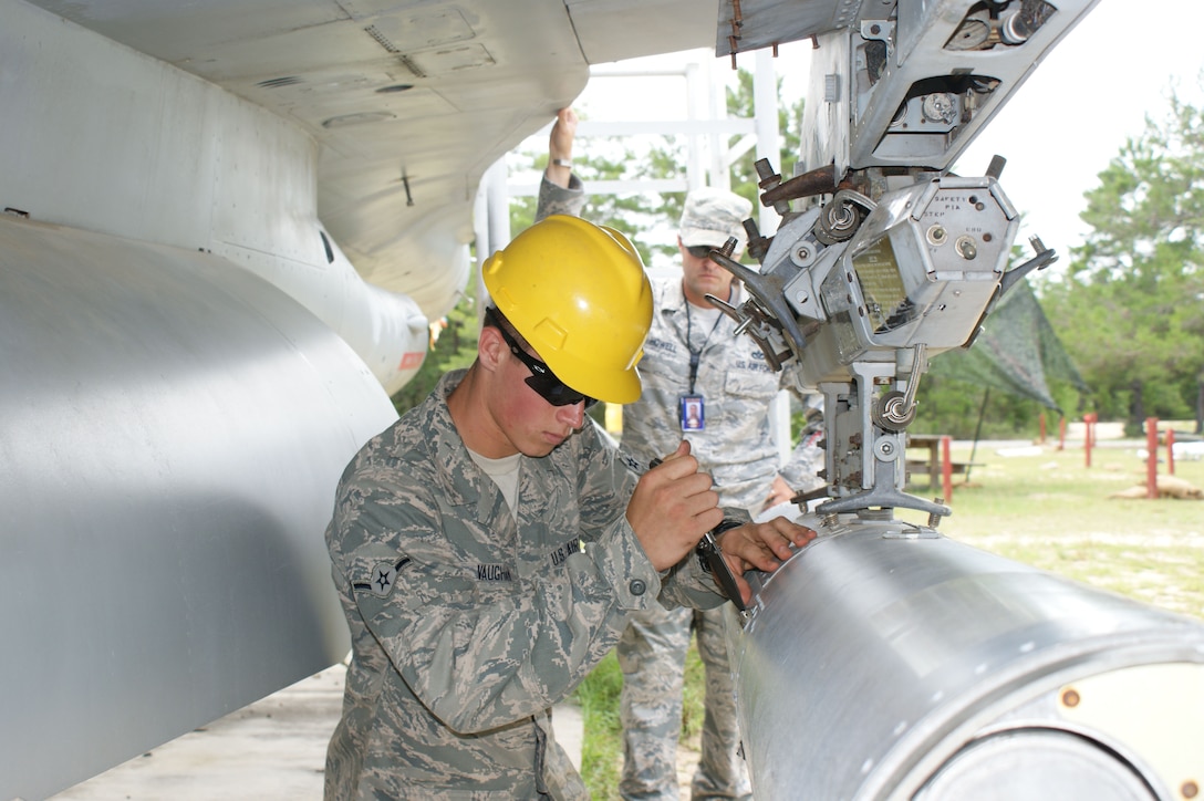 Airman Ryan Vaughn (foreground) gets set to download a hung MK-45 flare as Staff Sgt. Charles Howell evaluates during Air Division training at Naval School Explosive Ordnance Disposal Jul. 20, 2012 at Eglin Air Force Base, Florida.  During  the 26 academic days of Air Division training, students learn about aircraft explosive hazards as well as how to operate safely in and around all types of airframes.  (U.S. Air Force photo/Dan Hawkins)
