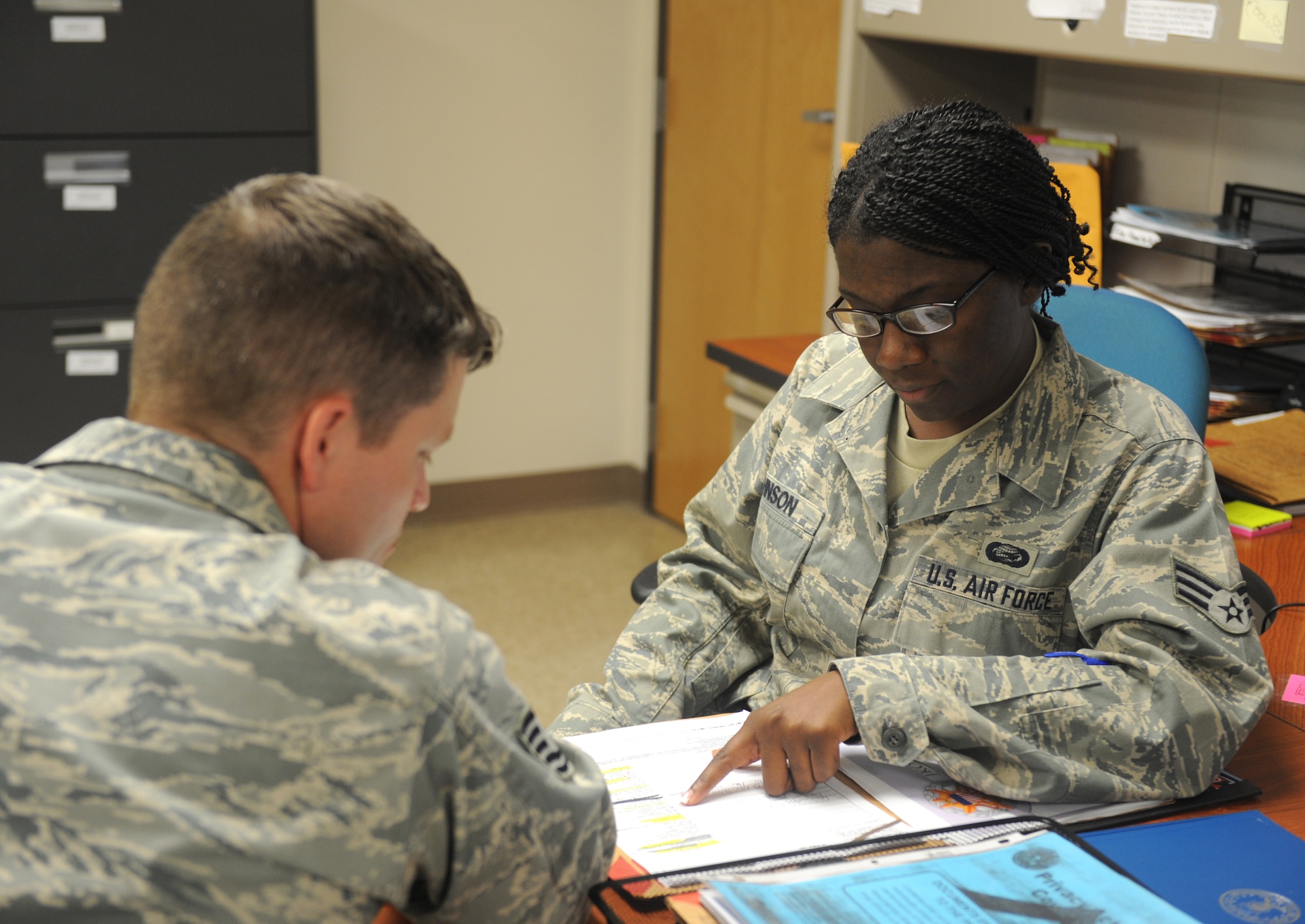 Senior Airman Cedric Johnson (right), 2nd Force Support Squadron military personnel section, goes over paperwork with a customer on Barksdale Air Force Base, La., July 30. Airmen from the MPS assist base personnel who are out-processing by directing them through the various steps of the process. (U.S. Air Force photo/Airman 1st Class Benjamin Gonsier)(RELEASED)