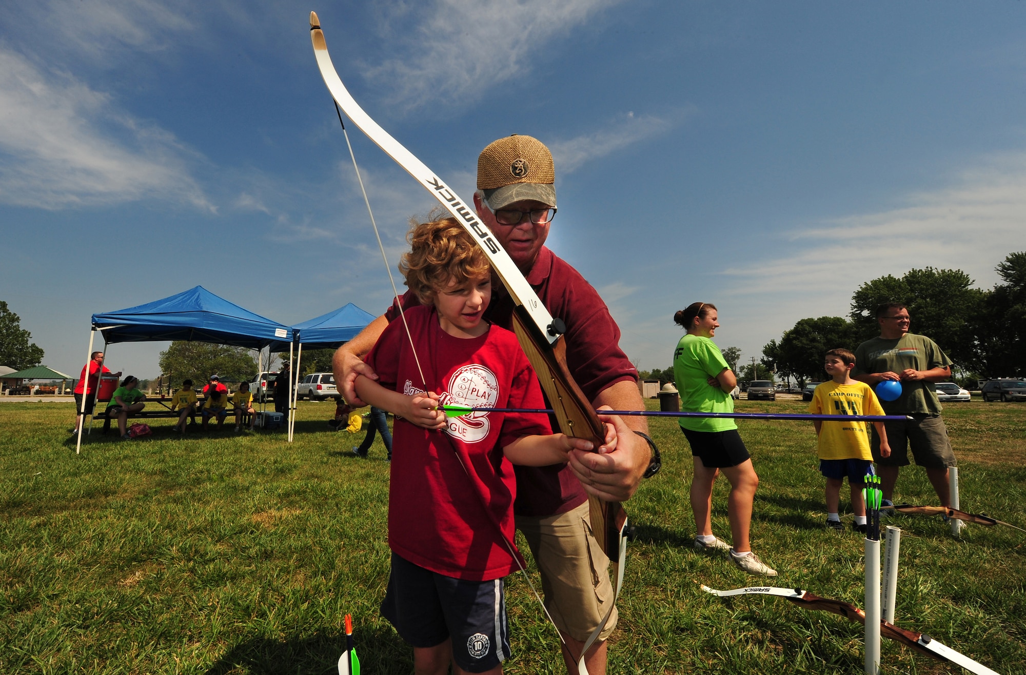 Eight year-old Mathew Baxter loads an arrow into a bow with the assistance of Team Offutt volunteer Sam Hines while attending the Exceptional Family Members Program’s Camp Offutt July 12 at Offutt AFB, Neb.  The two-day camp hosted by the Exceptional Family Member Program enhances teamwork abilities and builds friendships.  (U.S. Air Force photo by Josh Plueger/Released))