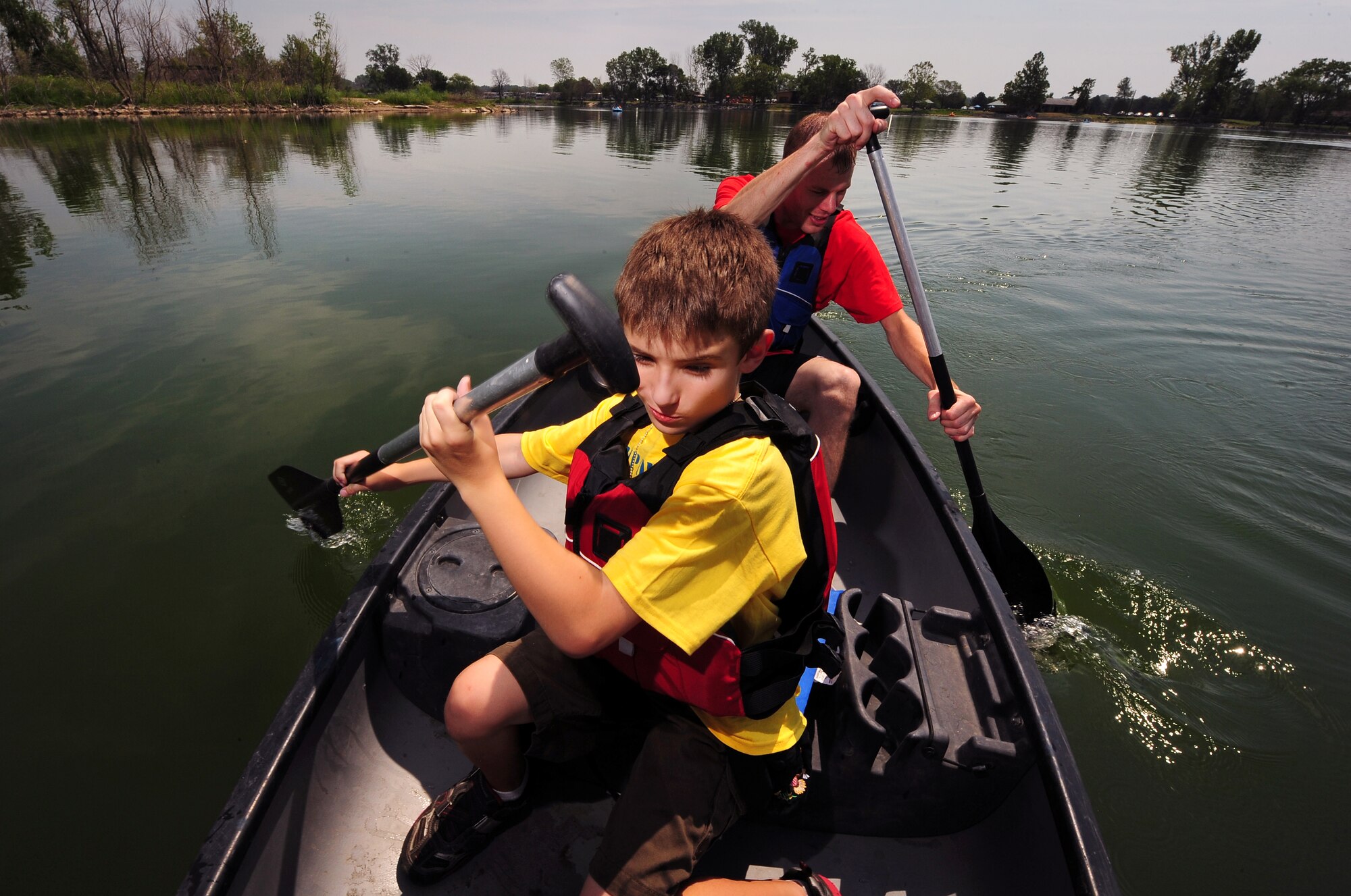 Nine year-old Chris Stewart and Offutt volunteer U.S. Air Force Tech. Sgt. Chris Wroegler navigate their canoe around the Offutt Base Lake during the Exceptional Family Members Program’s Camp Offutt July 12 at Offutt AFB, Neb.  This is the second year of the day camp which was founded by Offutt’s Exceptional Family Member Program was put on to enhance skills and build friendships.  (U.S. Air Force photo by Josh Plueger/Released)