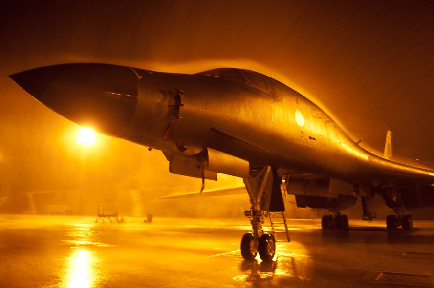 Lights in the aircraft parking area cast an eerie glow around a B-1 bomber standing at the ready during a summer rainstorm at Ellsworth Air Force Base, S.D., July 24, 2012. Ellsworth is home to 28 B-1 bombers and two of the Air Force’s three B-1 combat squadrons. (U.S. Air Force photo by Airman 1st Class Zachary Hada/Released)