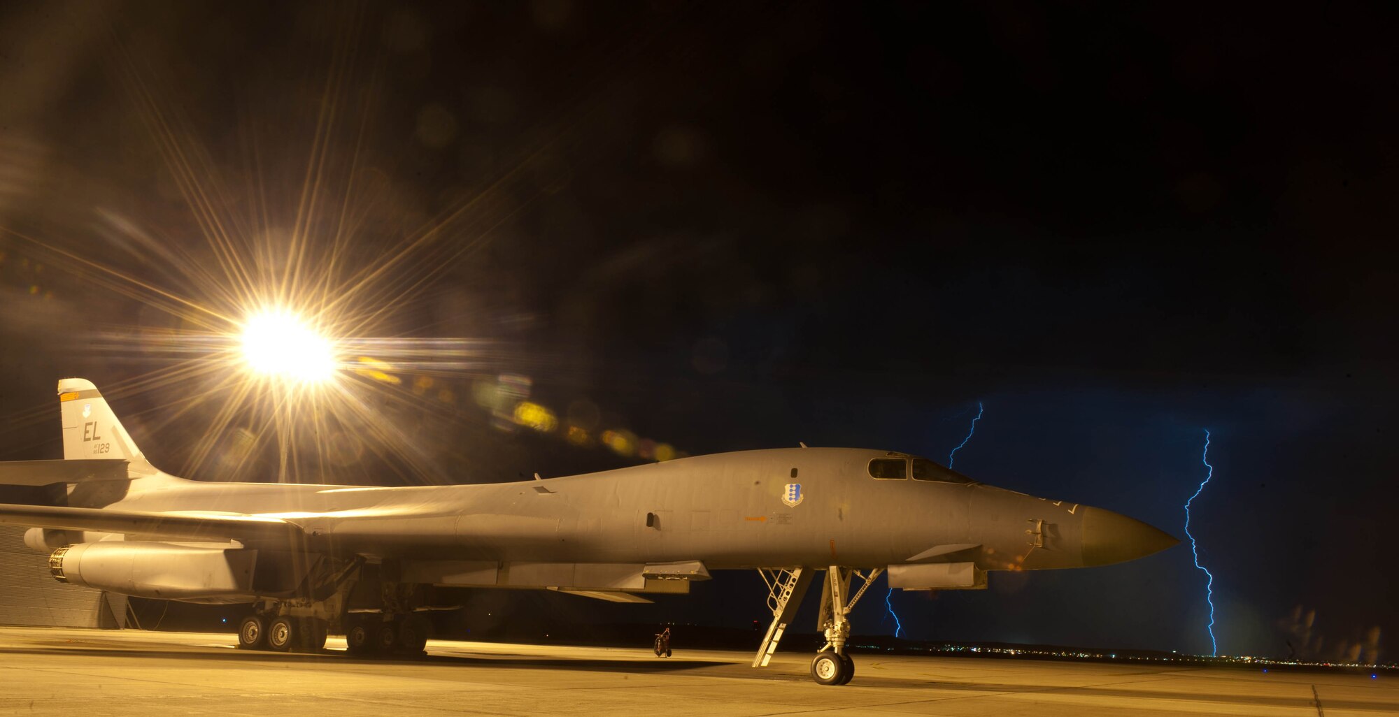 Lightning fills the sky behind a B-1 bomber during a late night thunderstorm at Ellsworth Air Force Base, S.D., July 24, 2012. The B-1 is the backbone of America’s long-range bomber force, and can rapidly deliver massive quantities of precision and non-precision weapons against enemy forces. (U.S. Air Force photo by Airman 1st Class Zachary Hada/Released)