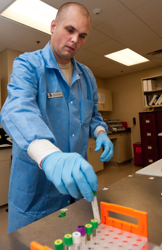 Tech. Sgt. Benjamin McReynolds, 28th Medical Support Squadron laboratory operations NCO in charge, places a blood specimen in a hold rack after its cycle through a chemistry analyzer in the clinical laboratory on Ellsworth Air Force Base, S.D., July 27, 2012. The lab technicians are responsible for analyzing specimens such as blood, urine and stool samples to determine the well-being of Airmen and families on Ellsworth. (U.S. Air Force photo by Airman 1st Class Kate Thornton/Released)