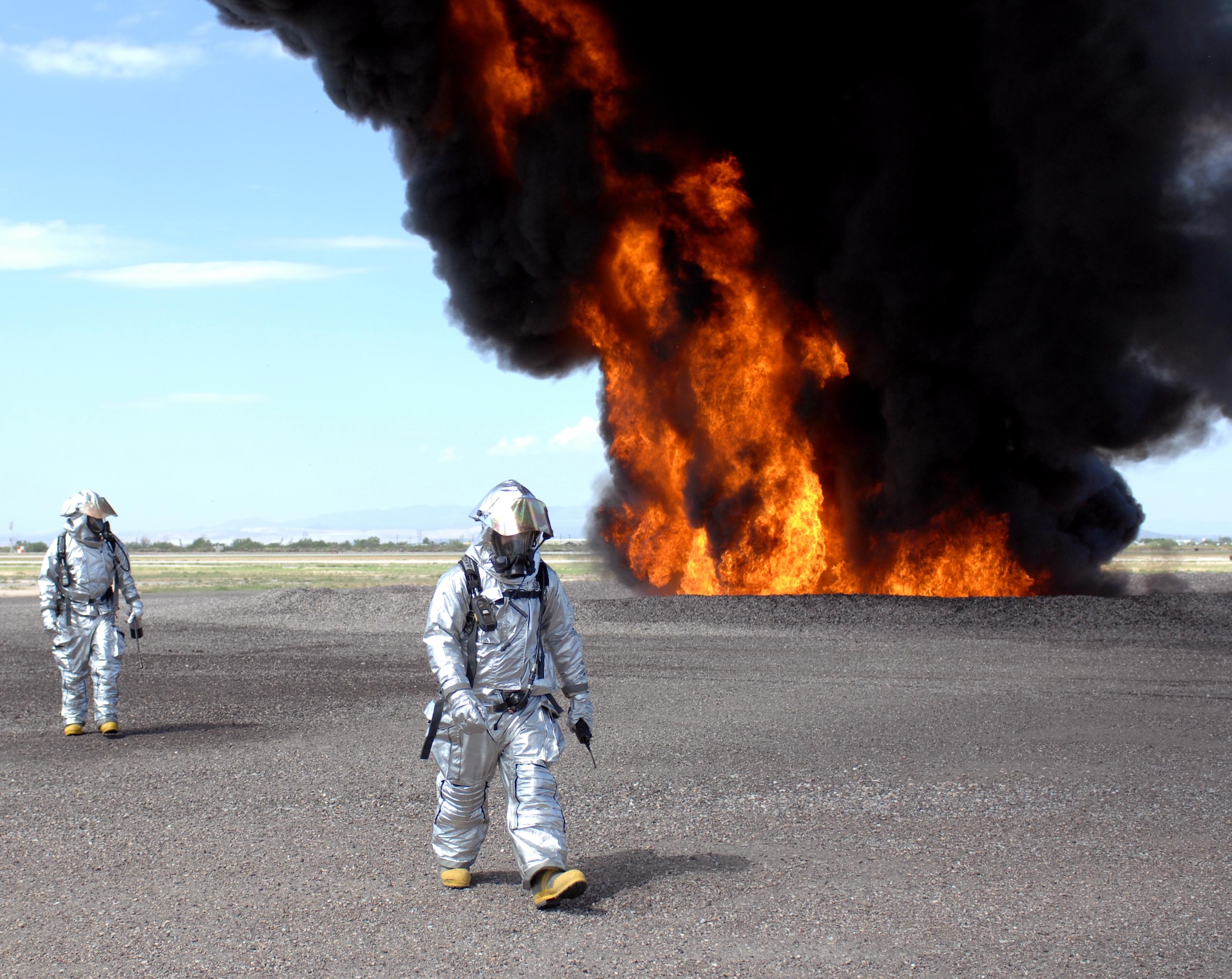 U.S. Air Force Tech. Sergeant Caleb Dacay, 355th Civil Engineer Squadron firefighter, (front) and Senior Airman Spencer Snodgrass, 355th CES firefighter, (rear) walk away from the fire they started under a mock A-10 during a training session at the D-M Regional Fire and Emergency Services Training Area on Davis-Monthan Air Force Base, Ariz., July 17, 2012. As members of the lighting crew their job was to light the fire so that other members of their squadron could put it out. (U.S. Air Force photo by Airman 1st Class Saphfire Cook)