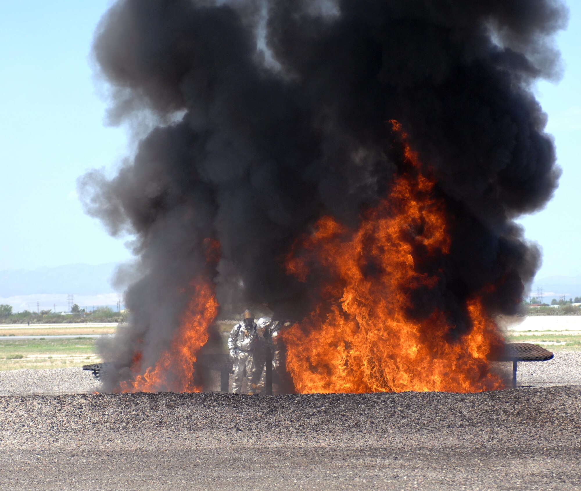 U.S. Air Force Senior Airman Gerald Roybal, 355th Civil Engineer Squadron firefighter, stands in the midst of a fire the lighting crew started during a training session at the D-M Regional Fire and Emergency Services Training Area on Davis-Monthan Air Force Base, Ariz., July 17, 2012. The fire was started under a metal frame, mock A-10 that the department uses for training purposes. (U.S. Air Force photo by Airman 1st Class Saphfire Cook)