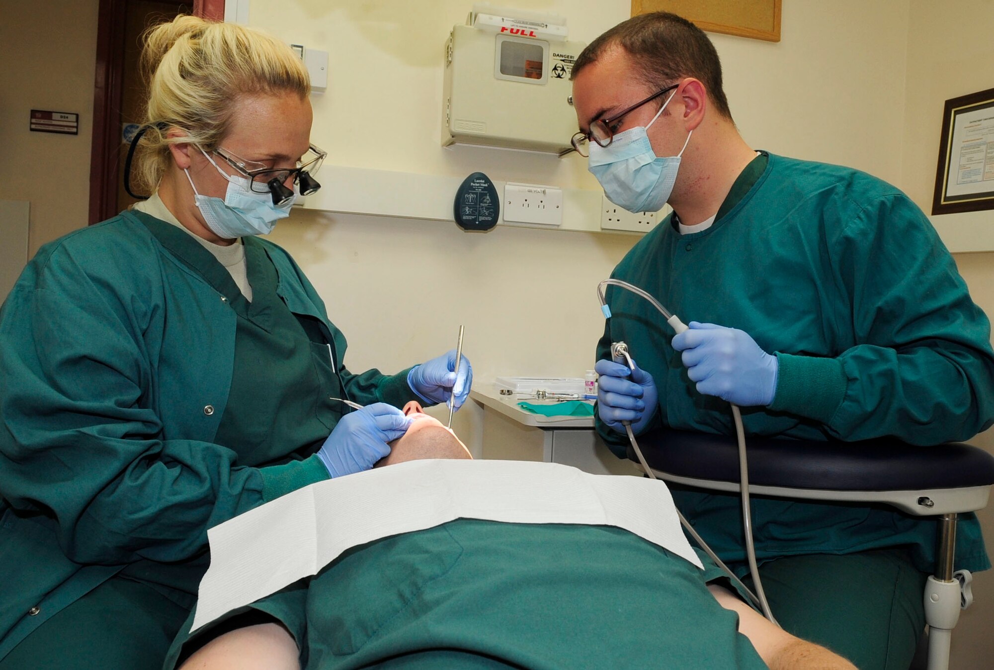 RAF MILDENHALL, England – Capt. (Dr.) Julie Robinson, (left) 48th Dental Squadron, performs a routine exam on Senior Airman Phillip Madison, 48th Dental Squadron dental technician, while assisted by Senior Airman Joseph Bateman, 48th Dental Squadron dental technician, during an internal training exercise at RAF Mildenhall July 30, 2012. The RAF Mildenhall dental clinic sees every active-duty Airman here annually. (U.S. Air Force photo Senior Airman Ethan Morgan)
