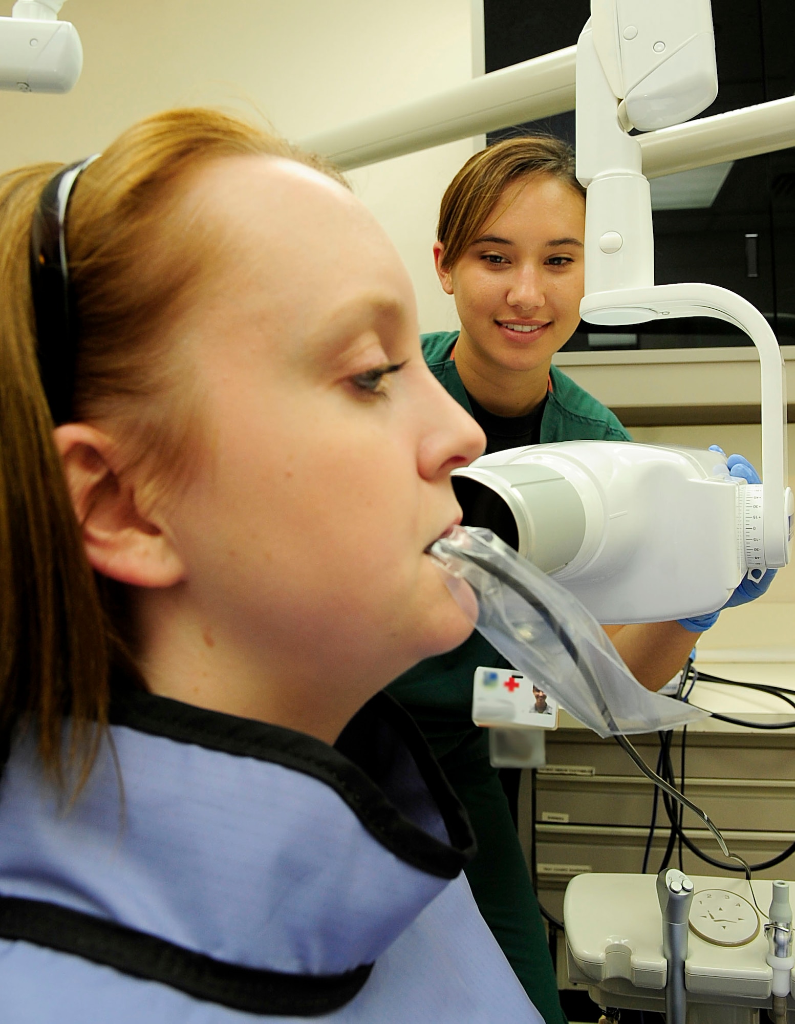 RAF MILDENHALL, England – Senior Airman Krystle Watson, (right) 48th Dental Squadron dental technician, places an X-ray tube head into position on Airman 1st Class Katrina Jackson, 48th Dental Squadron dental technician, to take an X-ray during an internal training exercise at RAF Mildenhall July 30, 2012. The RAF Mildenhall dental clinic roughly takes 105 X-rays of patients weekly. (U.S. Air Force photo Senior Airman Ethan Morgan) (Photo masked for security purposes)