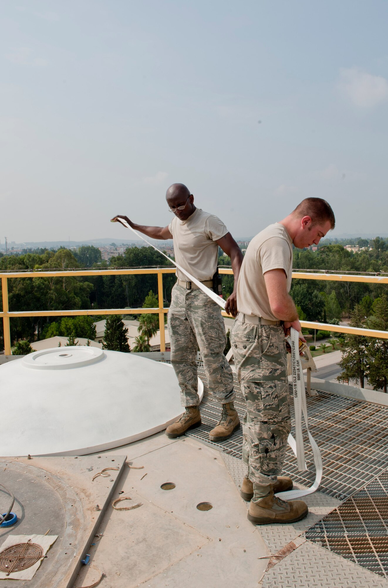 Staff Sgt. Lawrence Turgeon, right, and Senior Airman Michael Williams, 39th Communications Squadron ground radar maintenance technicians, unwind a strap on top of a weather radar tower July 27, 2012, at Incirlik Air Base, Turkey. The Tactical Weather Radar was replaced with the new Portable Doppler Radar system, first in U.S. Air Forces in Europe. The new system will enhance weather predictability for both U.S. and Turkish forces at Incirlik. (U.S. Air Force photo by Senior Airman Anthony Sanchelli/Released) 
