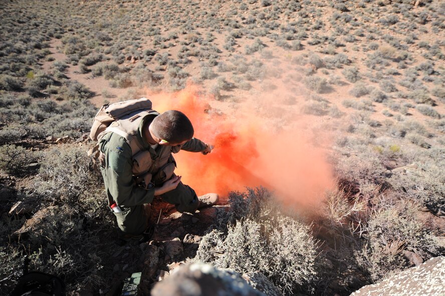 Using a smoke flare from his survival kit, U.S. Air Force 1st Lt. Kyle Harrington, a B-1 bomber pilot with the 34th Bomb Squadron at Ellsworth Air Force Base, S.D., signals rescue personnel at the Nevada Test and Training Range July 24, 2012.  Harrington used a mirror, smoke canisters and a radio during a combat search and rescue exercise scenario for Red Flag 12-4. (U.S. Air Force photo by Master Sgt. Sonny Cohrs) 