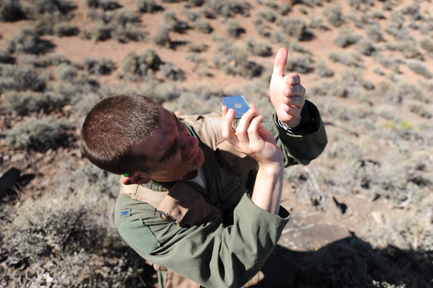 Using a signal mirror from his survival kit, U.S. Air Force 1st Lt. Kyle Harrington, a B-1 bomber pilot with the 34th Bomb Squadron at Ellsworth Air Force Base, S.D., signals rescue personnel at the Nevada Test and Training Range July 24, 2012.  Harrington used a mirror, smoke canisters and a radio during a combat search and rescue exercise scenario for Red Flag 12-4. (U.S. Air Force photo by Master Sgt. Sonny Cohrs) 