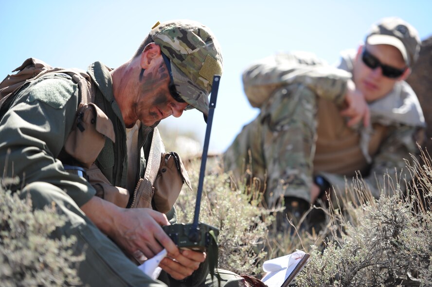 Using a radio to signal the rescue mission commander, U.S. Air Force 1st Lt. Kyle Harrington, a B-1 bomber pilot with the 34th Bomb Squadron at Ellsworth Air Force Base, S.D., relays his coordinates July 24, 2012, while U.S. Air Force Senior Airman Kevin Webb, a SERE specialist from the 22nd Training Squadron at Fairchild Air Force Base, Wash., observes.  According to Webb, the most critical thing for isolated personnel is to remain in constant contact with recovery assets.  (U.S. Air Force photo by Master Sgt. Sonny Cohrs) 
