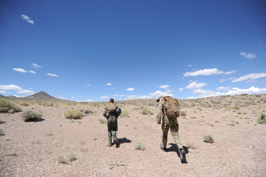 U.S. Air Force 1st Lt. Kyle Harrington, a B-1 bomber pilot with the 34th Bomb Squadron at Ellsworth Air Force Base, S.D., and U.S. Air Force Senior Airman Kevin Webb, a SERE specialist from the 22nd Training Squadron at Fairchild Air Force Base, Wash., run into the desert at the Nevada Test and Training Range July 24, 2012, during a combat search and rescue exercise scenario.  Harrington is simulating a downed aircrew member and Webb is serving as an observer controller to ensure safety at the NTTR.  (U.S. Air Force photo by Master Sgt. Sonny Cohrs)