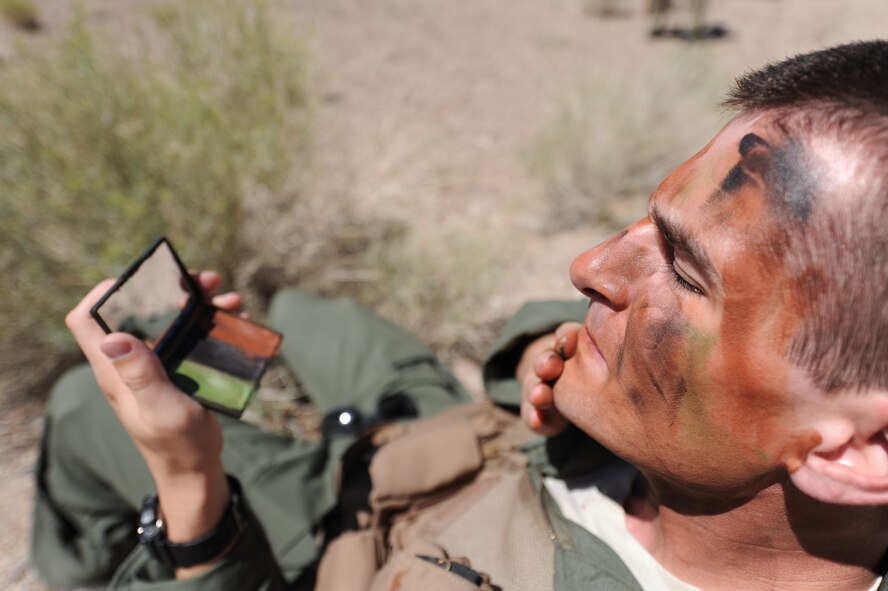 Serving as a downed aircrew member during a combat search and rescue exercise scenario, U.S. Air Force 1st Lt. Kyle Harrington, applies camouflage face paint to conceal himself at the Nevada Test and Training Range July 24, 2012. Harrington is a B-1 bomber pilot with the 34th Bomb Squadron at Ellsworth Air Force Base, S.D., deployed to Nellis Air Force Base, Nev., for exercise Red Flag 12-4.  (U.S. Air Force photo by Master Sgt. Sonny Cohrs)