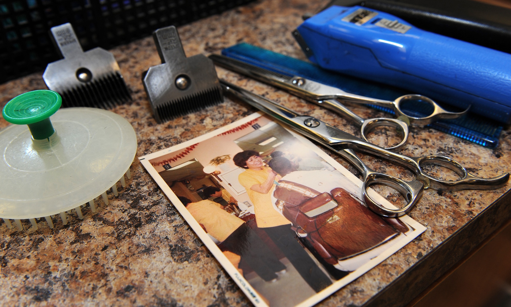 A 40 year-old photo of Kazumi Oshiro, Army & Air Force Exchange Service barber shop manager, lies beside barber tools on Kadena Air Base, Japan, July 18, 2012. In 1965, when she started working, haircuts were 25 cents and shaving and shampooing cost 10 cents. (U.S. Air Force photo/Junko Kinjo)