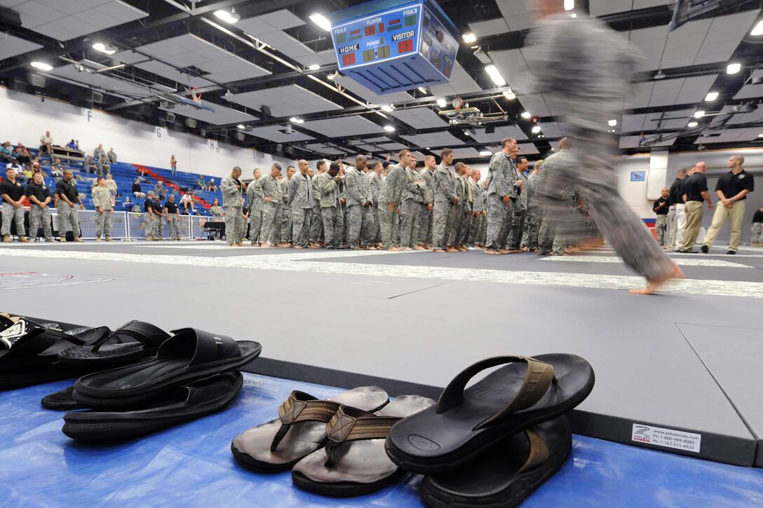 A service member runs past a line of sandals to join the other competitors in formation during the opening round of the 2012 U.S. Army Combatives Championship competition on Fort Hood, Texas, July 25, 2012.