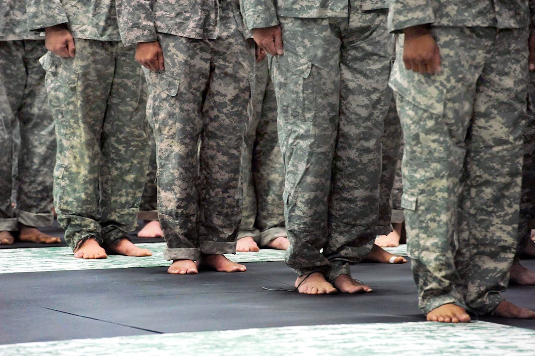 Service members stand in formation barefoot during the opening ceremony of the 2012 U.S. Army Combatives Championship competition on Fort Hood, Texas, July 25, 2012.