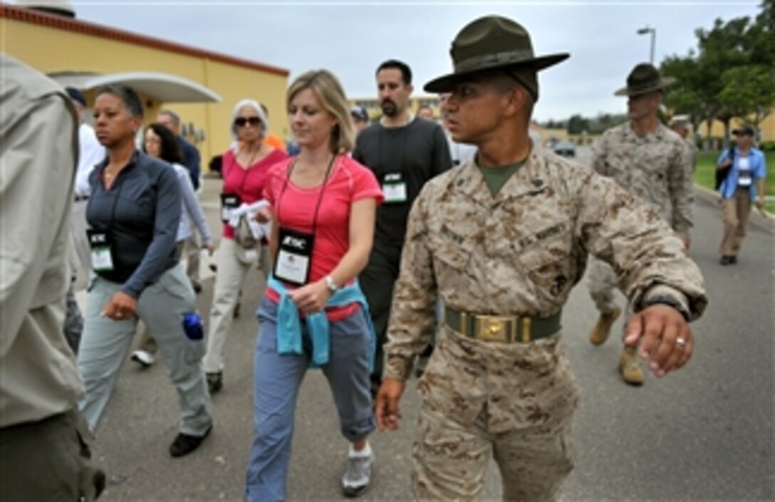 Participants of the DoD's Joint Civilian Orientation Conference march under the watchful eye of Drill Instructor Sgt. Gustava Brown at the Marine Corps Recruit Depot in San Diego on July 25, 2012.  The participants were surprised by the stern welcome given to them as they were treated to a standard new recruit shakedown at the base's receiving barracks.  