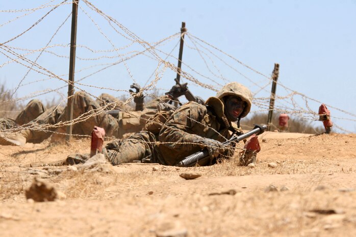 A recruit low-crawls underneath barbed-wire as he goes through Copeland's Fire Team Assault Course July 26 at Edson Range aboard Marine Corps Base Camp Pendleton, Calif. The course gives the recruits a sense of realism as they maneuver their way through trenches, over walls and through tunnels to complete the course.