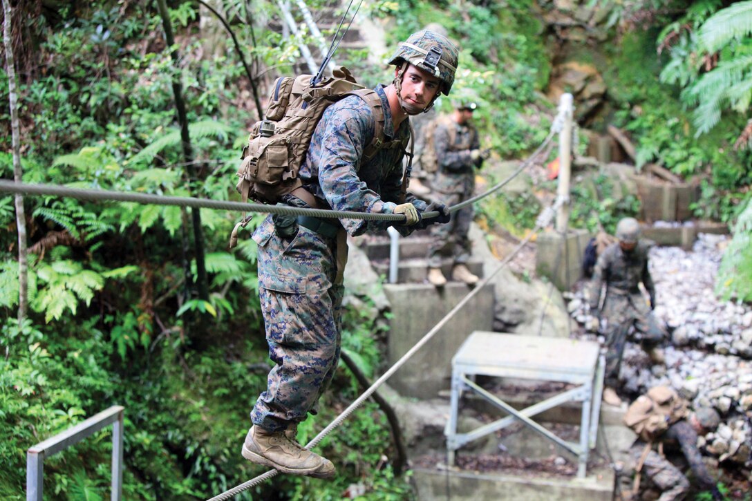 Lance Cpl. Matthew J. Vito traverses a rope bridge to cross a ravine during land navigation operation training at Camp Gonsalves July 24. Vito is an anti-tank missileman with the battalion. The Marines spent four days finding check points and traveling through the jungle of Okinawa. 
