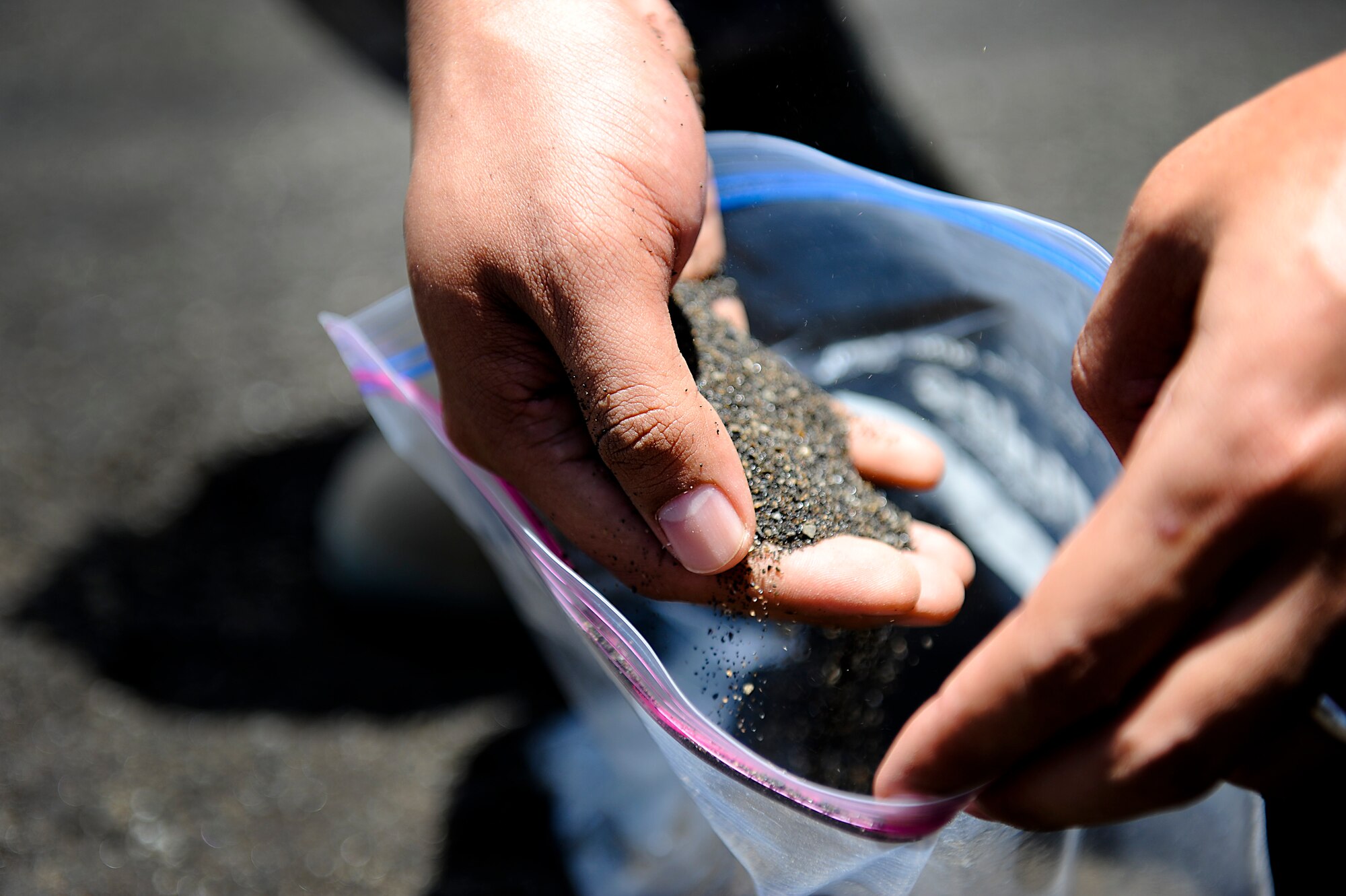 A U.S. Air Force Airman from the 18th Maintenance Group collects black volcanic sand from the beaches of Iwo To, Japan, formerly known as Iwo Jima, during a tour of the island July 26, 2012. In an effort to further the professional military education of the 18th Wing Airmen, the 18th Wing History Office has begun giving tours of the island periodically. This was the second tour the 18th HO has conducted. (U.S. Air Force photo/ Airman 1st Class Maeson L. Elleman)