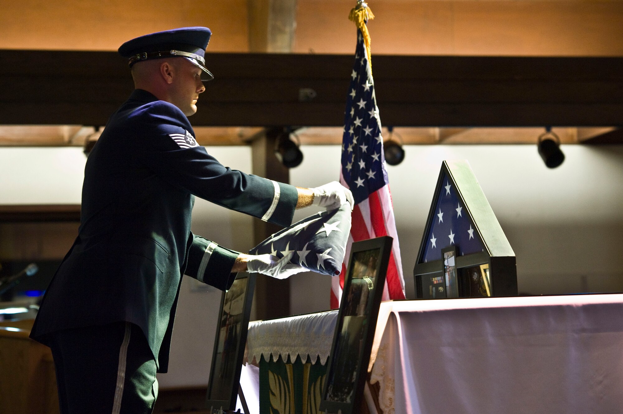 U.S. Air Force Tech. Sgt. Phillip Ridenour, 99th Force Support Squadron non-commissioned officer in charge base honor guard, puts a flag  on an altar during a memorial service held for Senior Airman Derek Moore, 757th Aircraft Maintenance Squadron electrical and environmental systems journeyman July 27, 2012, at Nellis Air Force Base, Nev. Moore was assigned to the 757th AMXS since Sept. 2009(U.S. Air Force photo by Airman 1st Class Christopher Tam)