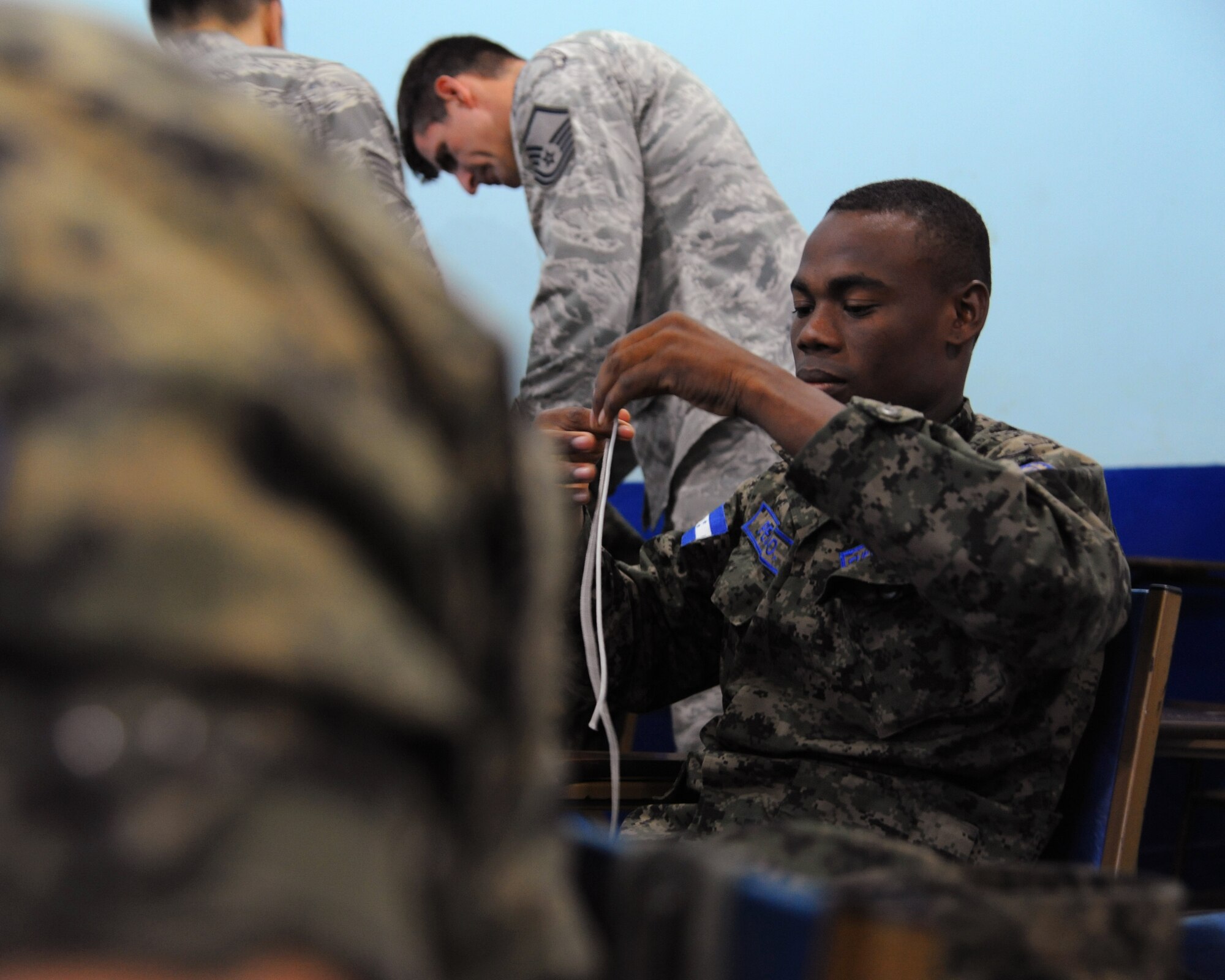 Cavo de Seguridad Area Santiago Peri-Ortiz, a Honduran Airman, practices tying survival knots as part of exchanging ideas with Master Sgt. Troy Daland in Tegucigalpa, Honduras.  Over the next 30 days Peri-Ortiz and his fellow Honduran Airmen will continue trading ideas and experiences while working together to build relationships and partner capacity between the U.S. and Honduran air forces.  (U.S. Air Force photo/Staff Sgt. James Stewart)