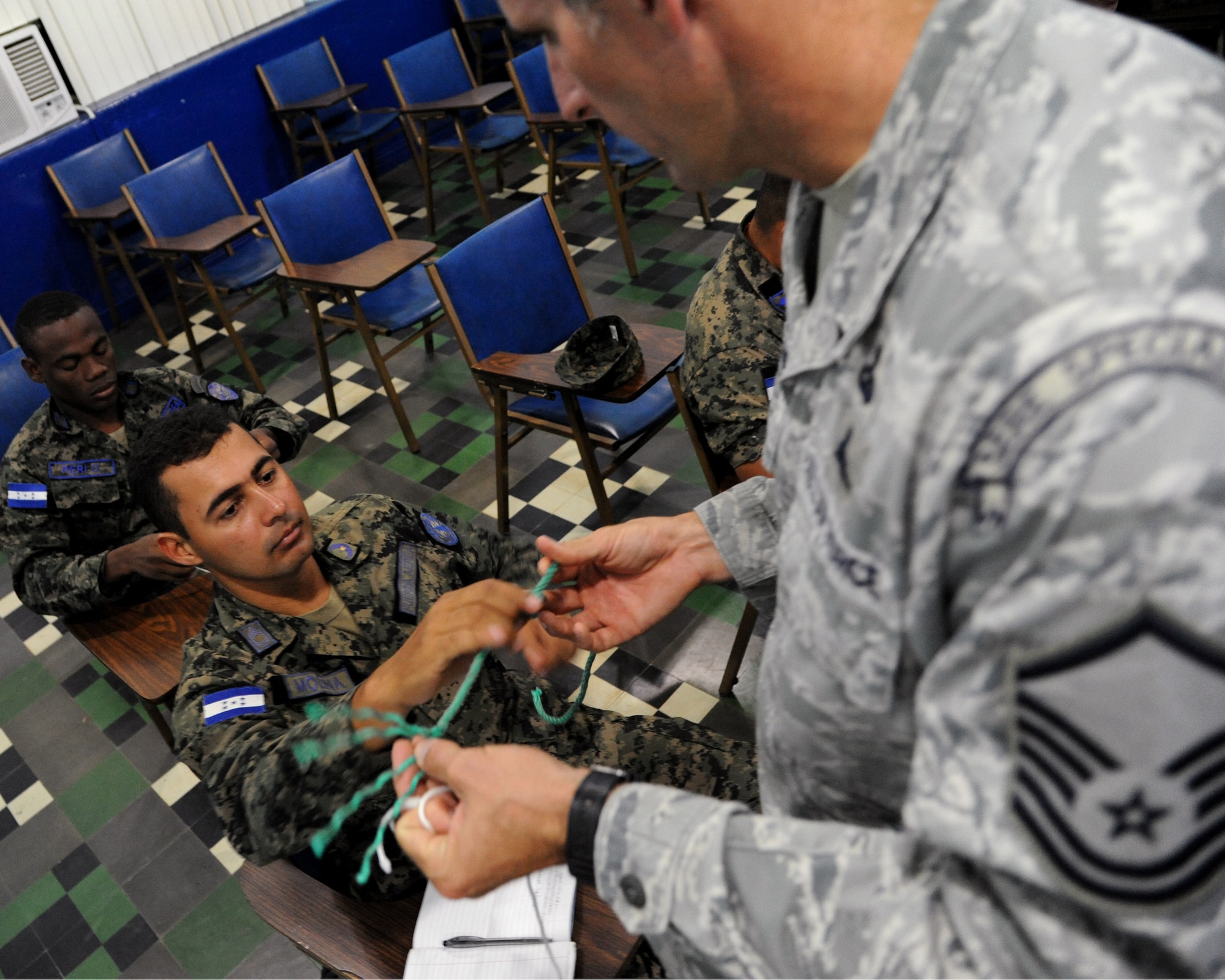 Master Sgt. Troy Daland, a SERE Specialist with the 571st Mobility Support Advisory Squadron, works with Honduran Airmen in Tegucigalpa, Honduras exchanging knowledge about fashioning knots used for survival situations.  Over the next 30 days Daland and his Honduran counterparts will continue trading ideas and experiences while working together to build relationships and partner capacity between the U.S. and Honduran air forces.  (U.S. Air Force photo/Staff Sgt. James Stewart)