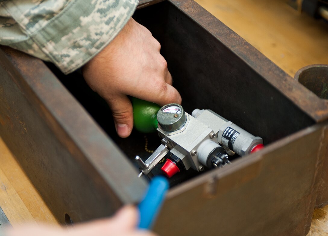 Senior Airman Benjamin Ledbetter, 28th Maintenance Squadron electro-environmental systems technician, places an emergency bailout oxygen bottle in an explosive proof box to test it for any problems at Ellsworth Air Force Base, S.D., July 27, 2012. The oxygen bottle is tested to ensure that if a B-1 aircrew member had to eject at extreme elevation, he or she would have oxygen to be able to breathe. (U.S. Air Force photo by Airman 1st Class Alystria Maurer/Released)