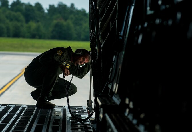 Chief Master Sgt. Damian Fox, 16th Airlift Squadron, 437th Airlift Wing operations group superintendent, communicates with pilots to back up the C-17 Globemaster III during a training flight July 25, 2012 at Joint Base Charleston - Air Base, S.C. Fox retired on July 27, 2012, after 30 years of service. (U.S. Air Force photo by Airman 1st Class George Goslin/Released)