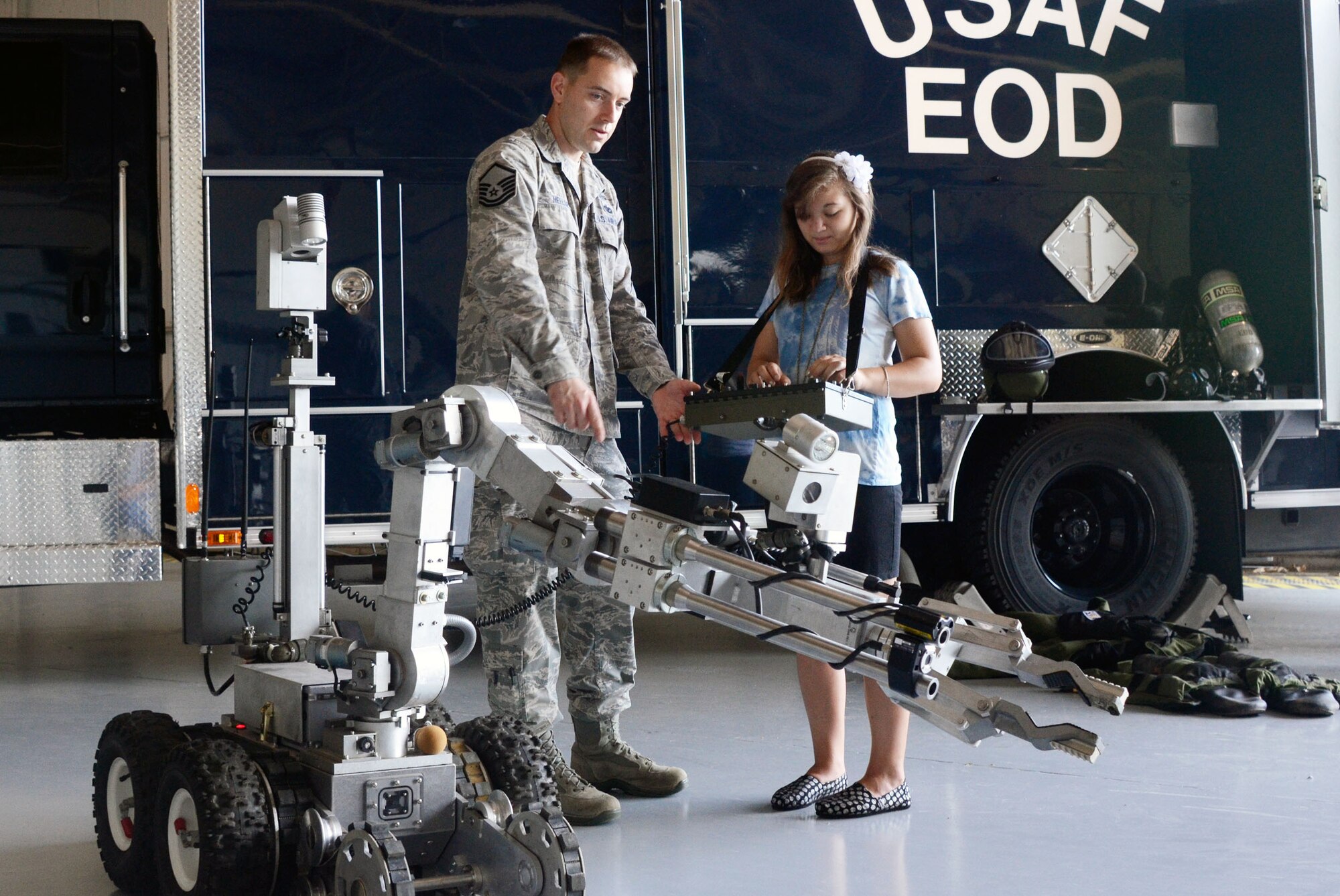 Master Sgt. Jason Mellor, from the 94th Civil Engineering Squadron, Explosive Ordinance Disposal Flight, helps Sierra Rose operate the bomb disposal robot during the Bring Your Kids to Work Day July 27. Personnel were able to bring their kids to work centers and then to a hangar for hands-on experience at displays fire department, explosive ordnance and security forces as well as a C-130 simulator demonstration. (U.S. Air Force photo/Don Peek)