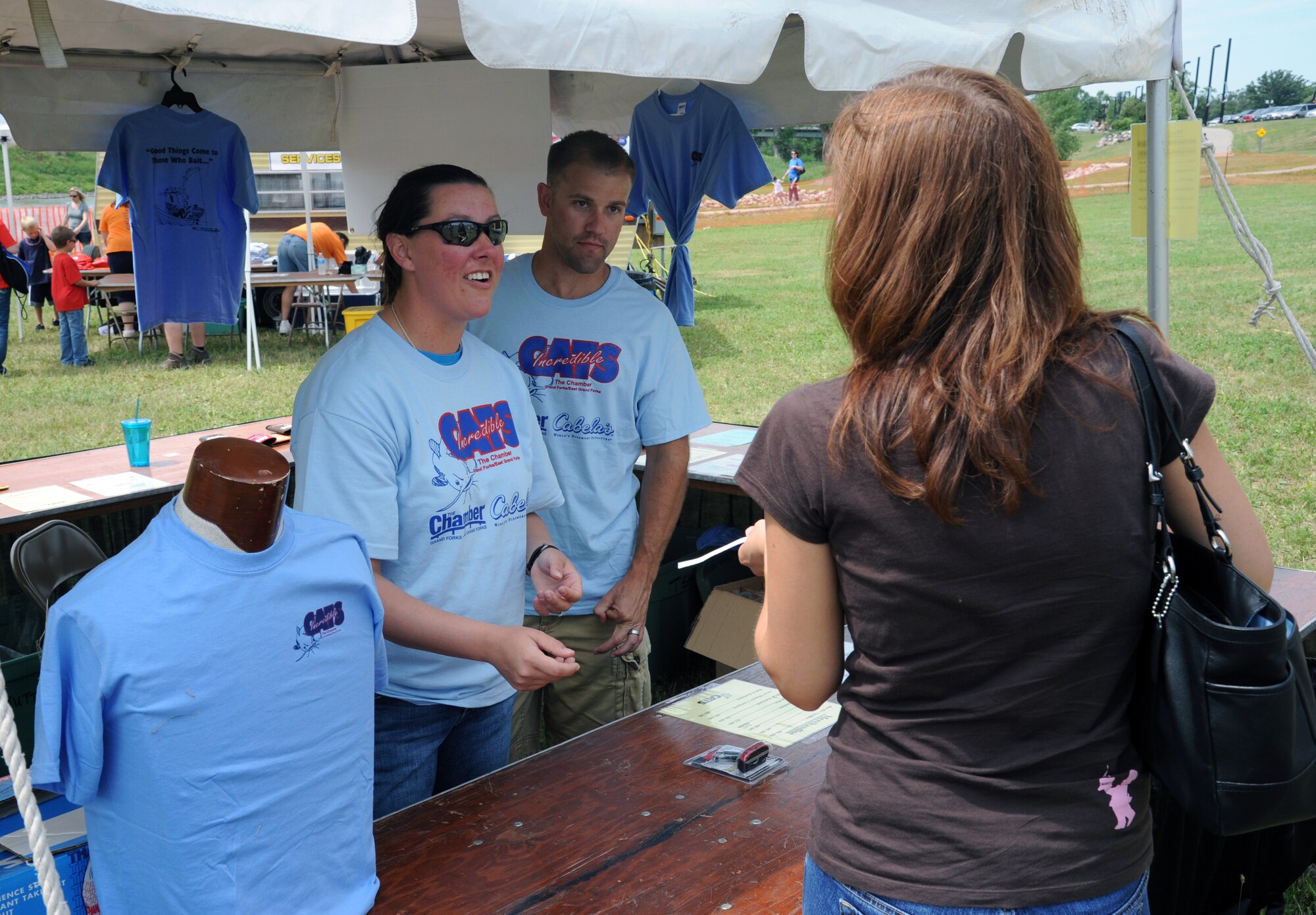 Staff Sgt. Jackie Mendenhall, left, and Senior Airman Jonathan Turcotte, both members of the 319th Security Forces Squadron at Grand Forks Air Force Base, N.D., assist a visitor while volunteering at the 25th Annual CATS Incredible Fishing Tournament on July 28, 2012, in East Grand Forks, Minn. More than 100 volunteers from the base assisted with the July 27-29 event.

