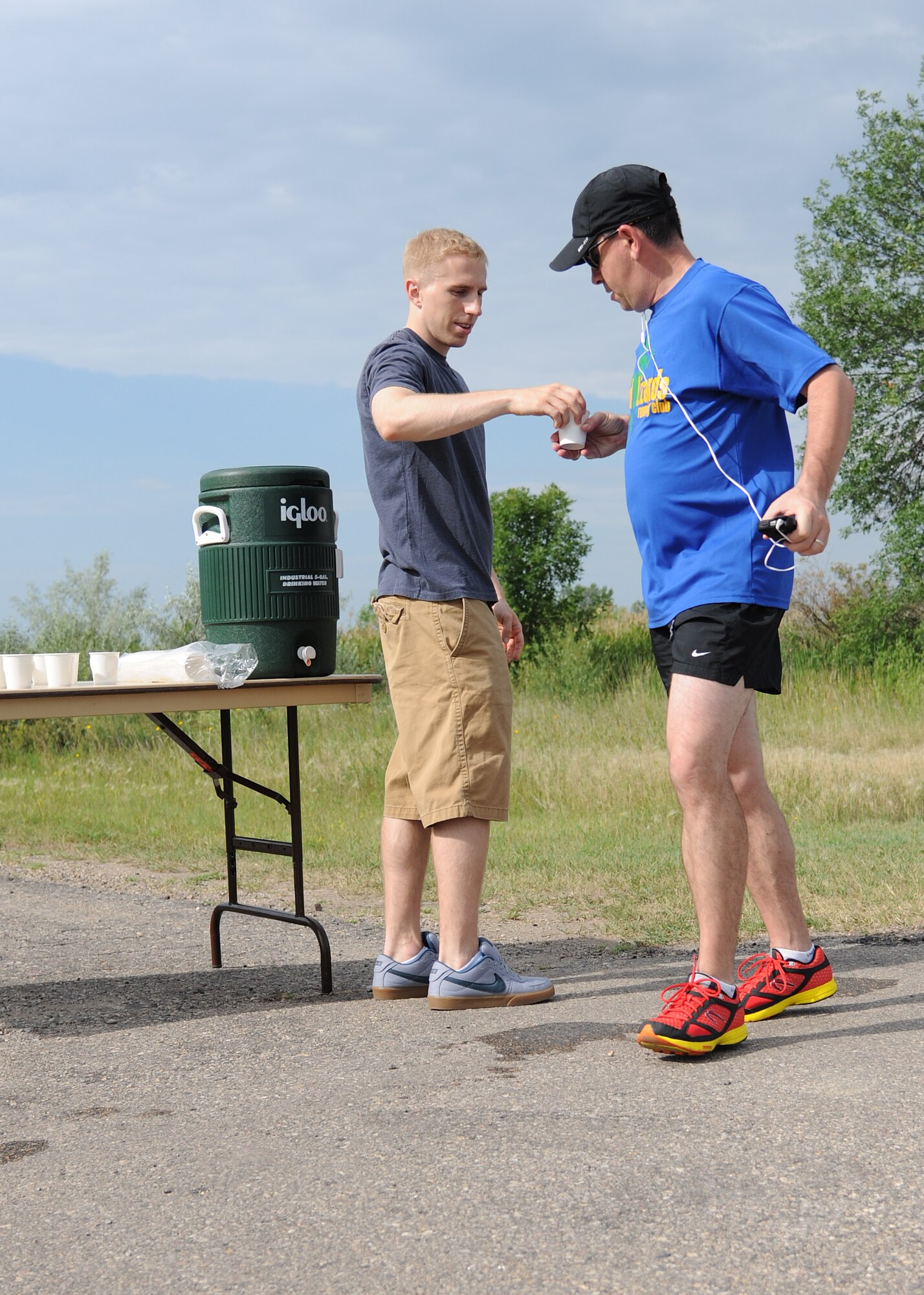 Airman 1st Class Paul Black, 319th Logistics Readiness Squadron, hands water to Chaplain (Capt.) Todd Leathermon, 319th Air Base Wing Chaplain Corps, while participating in the 2012 Grand Forks Air Force Base Triathlon on July 28, 2012, on Grand Forks Air Force Base, N.D.  Twenty-one individuals and five teams competed in the event. (U.S. Air Force photo/Airman 1st Class Ashley N. Taylor) 