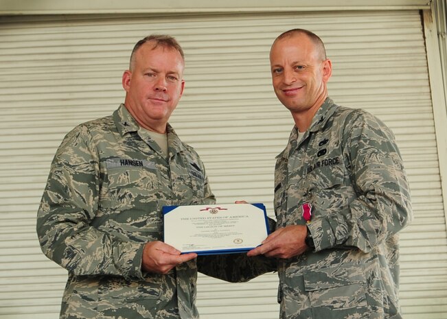 Colonel Erik Hansen, 437th Airlift Wing commander, passes the 437th Maintenance Group guidon to Col. Dennis Dabney, incoming 437th MG commander, during the 437th MXG Change of Command ceremony, July 27, 2012, at Joint Base Charleston - Air Base, S.C. The passing of the guidon symbolizes the changing of a command. (U.S. Air Force photo/ Staff Sgt. Katie Gieratz)