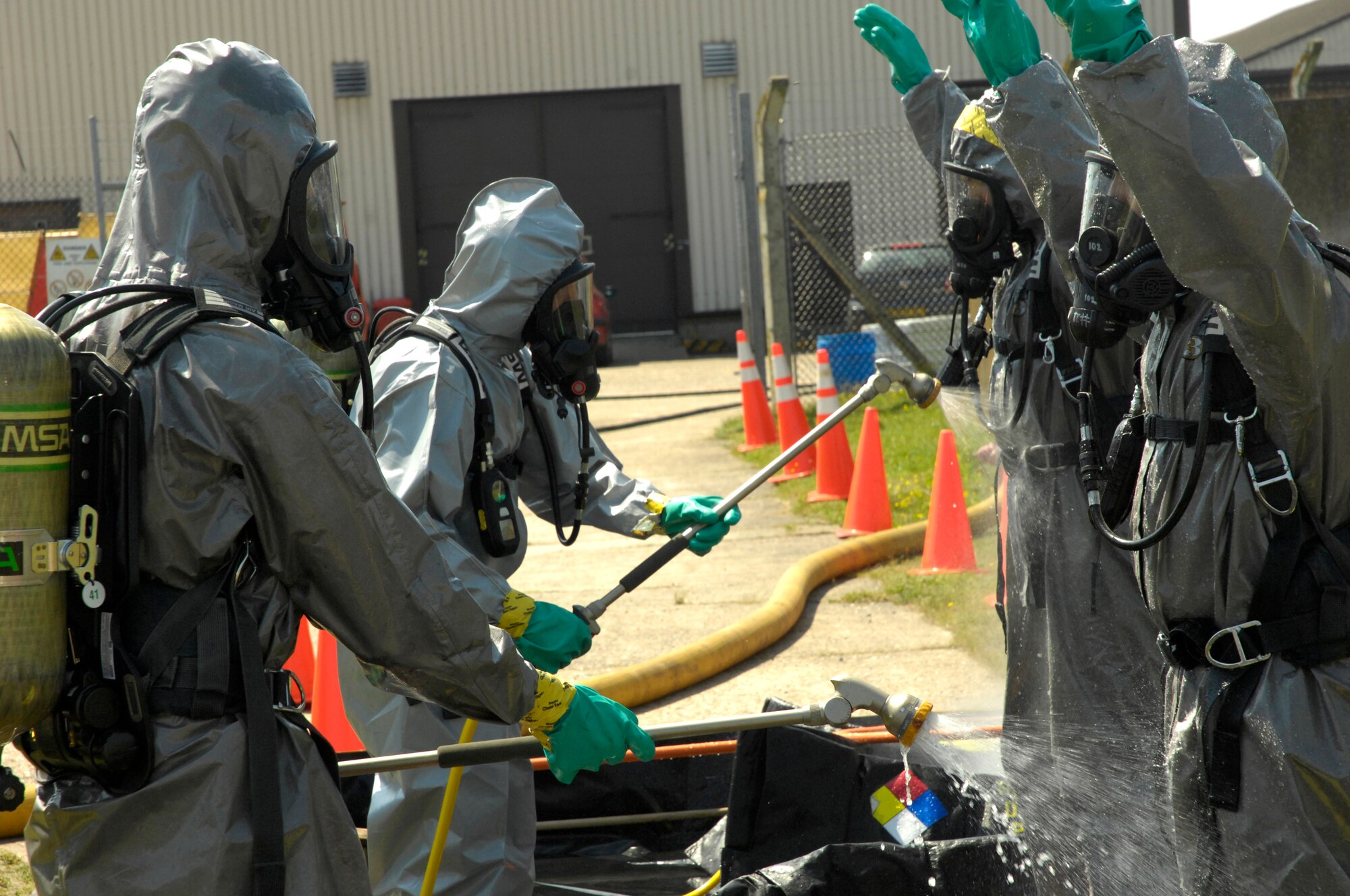 ROYAL AIR FORCE LAKENHEATH, England - Members of the 48th Civil Engineer Squadron spray each other down after processing two hazardous material technician entry teams through a decontamination system here July 26, 2012. The 48th CES responded to a HAZMAT incident after several large batteries were found cracked and leaking acid. (U.S. Air Force photo by Tech. Sgt. Zachary Melin)