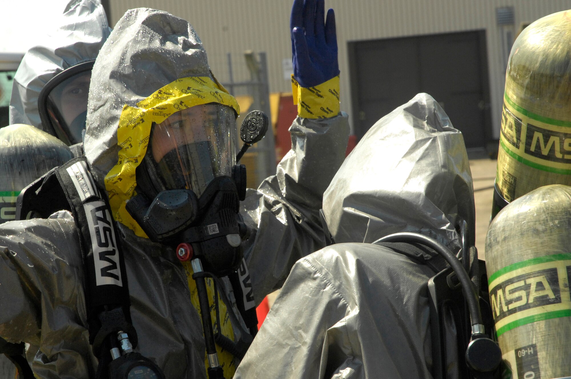 ROYAL AIR FORCE LAKENHEATH, England – Senior Airman Jessica Paulson, 48th Civil Engineer Squadron emergency management training monitor and hazardous material technician entry team member, raises her arms as Airman 1st Class Ashley Eisenbarth, 48th CES firefighter, helps to carefully remove her HAZMAT suit here July 26, 2012. The 48th CES responded to a HAZMAT incident after several large batteries were found cracked and leaking acid. (U.S. Air Force photo by Tech. Sgt. Zachary Melin)