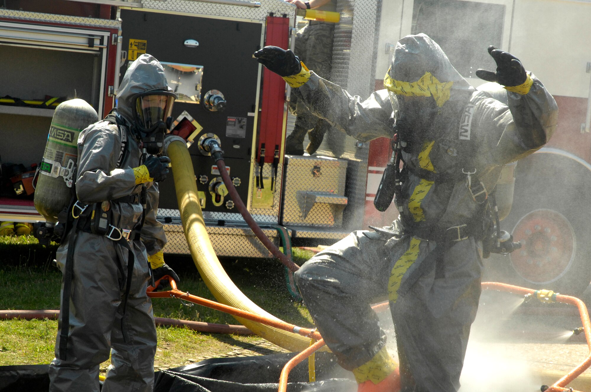 ROYAL AIR FORCE LAKENHEATH, England – Staff Sgt. Peter Torres (right), 48th Civil Engineer Squadron NCO in charge of emergency management logistics and hazardous material technician entry team member, lifts his boot to ensure all HAZMAT is washed off while Airman 1st Class Ashley Eisenbarth, 48th CES firefighter, maneuvers one side of a decontamination station here July 26, 2012. The 48th CES responded to a HAZMAT incident after several large batteries were found cracked and leaking acid. (U.S. Air Force photo by Tech. Sgt. Zachary Melin)