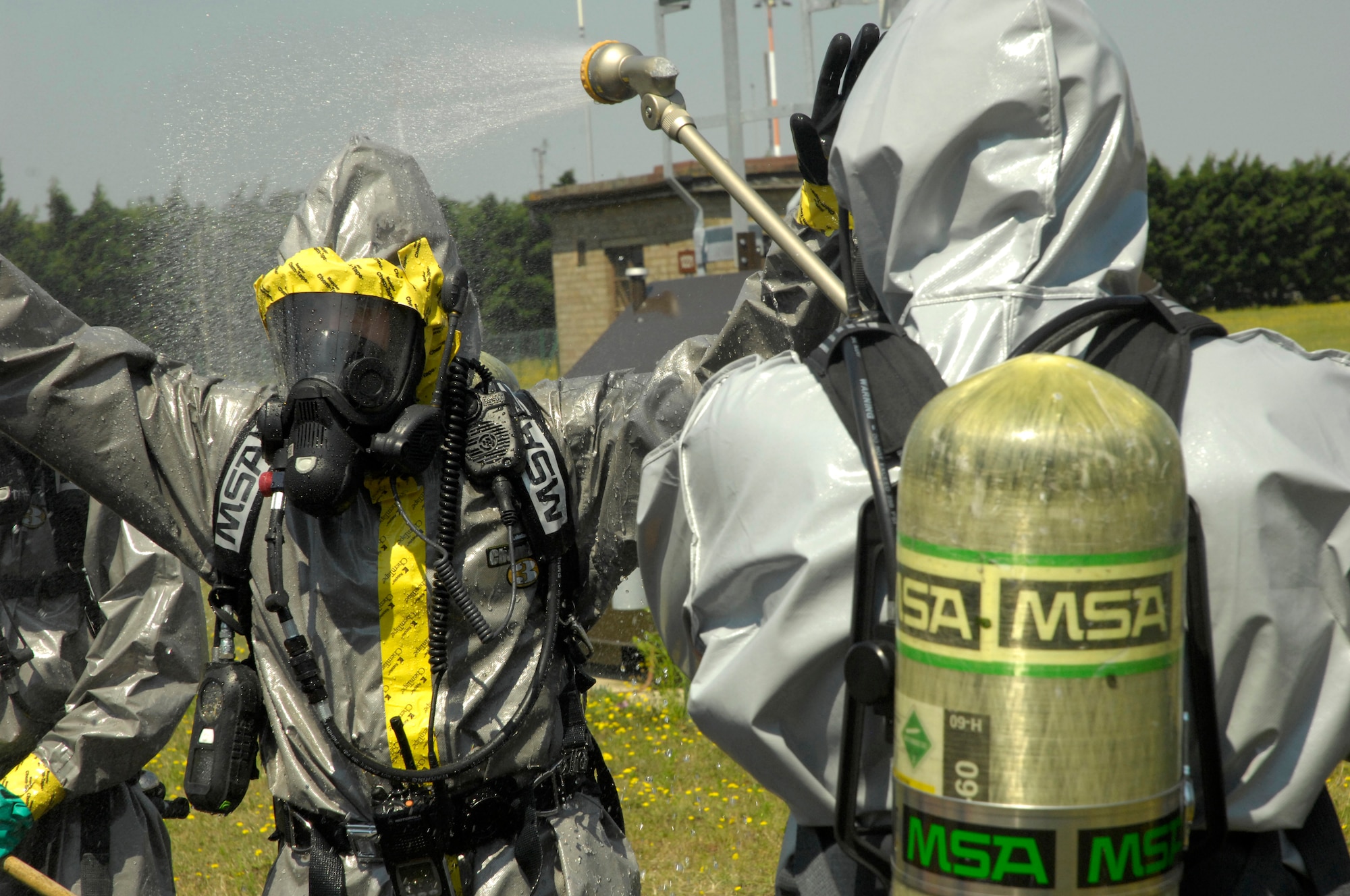 ROYAL AIR FORCE LAKENHEATH, England – A 48th Civil Engineer Squadron hazardous material technician entry team member is sprayed down by a 48th CES firefighter as part of the decontamination process to remove potential HAZMAT here July 26, 2012. The 48th CES responded to a HAZMAT incident after several large batteries were found cracked and leaking acid. (U.S. Air Force photo by Tech. Sgt. Zachary Melin)