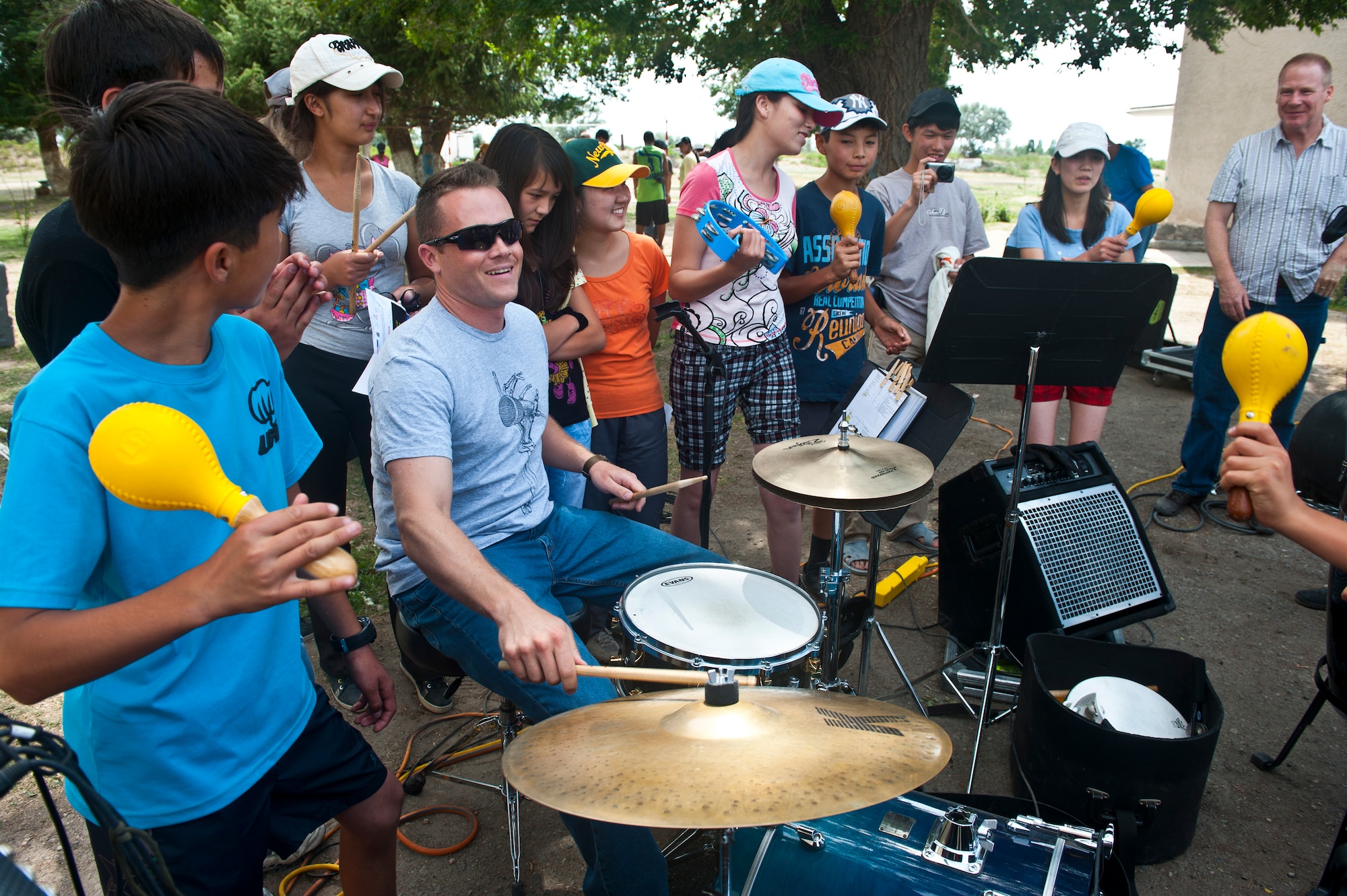 Senior Airman Simon Thomsen plays the drums for Kyrgyz Republic children after the U.S. Air Forces Central Band "Vector" performance at the Mayak Camp, Kyrgyzstan, July 23, 2012. After the concert, Vector band members interacted with the children and played different instruments with them. Thomsen is a drummer deployed out of the Channel Islands Air National Guard Station, Calif. and is a native of Los Angeles. (U.S. Air Force photo/Senior Airman Brett Clashman)